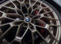 Close-up of a metallic bronze BMW M2 CS wheel with a geometric spoke pattern and a visible red brake caliper behind it, highlighting the sporty details at its World Premiere.