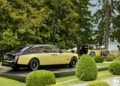 Two yellow and black Rolls-Royce cars—one a modern Rolls-Royce Phantom and the other vintage—are displayed outdoors on platforms surrounded by greenery, evoking a sense of timeless elegance at Villa d'Este.