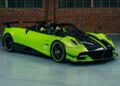A bright green and black Pagani hypercar is parked indoors in front of a brick wall and large windows.