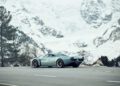 A silver Pagani sports car parked on a mountain road, with snow-covered peaks and trees in the background, evokes the spirit of Motor Valley Fest and the world of hypercars.