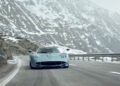 A silver Pagani hypercar drives on a winding mountain road with snow-covered rocky slopes in the background, capturing the spirit of Motor Valley Fest.