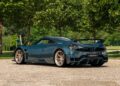 A teal Pagani Huayra Epitome is parked on a cobblestone surface at Villa d’Este, with lush trees and greenery in the background.