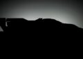 Silhouette of a Porsche 963 RSP race car with a large rear wing, set against a gradient background transitioning from dark to light—perfect for fans of legendary billionaire race team boss Roger Penske.