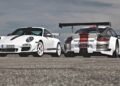 Two white Porsche 911 sports cars with red accents, including the last production Porsche with a naturally-aspirated Mezger flat-six engine, are parked on a paved surface—one facing forward, the other displaying its large rear spoiler.