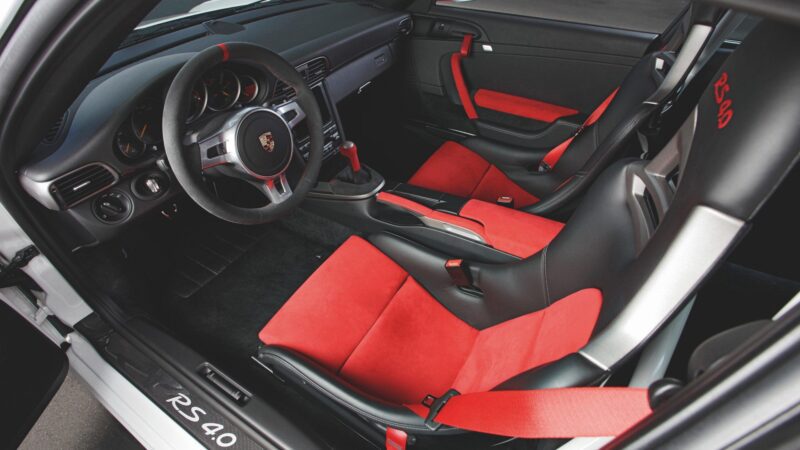 Interior of the last production Porsche with a naturally-aspirated Mezger flat-six engine, featuring black and red bucket seats, RS 4.0 stitching, manual transmission, and a sport steering wheel.