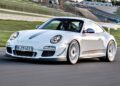 A white Porsche 911 GT3 RS, the last production Porsche with a naturally-aspirated Mezger flat-six engine, speeds along the racetrack, showcasing its rear wing and red accents.