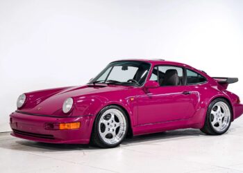 A magenta Porsche 911 Turbo with wide fenders and polished wheels is parked in a white studio setting, highlighting one of the most iconic Porsche models.