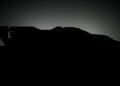 Silhouette of an exotic race car with a large rear wing, reminiscent of the Porsche 963 RSP, set against a gradient dark background.