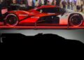 A red, black, and white Porsche 963 RSP exotic car is on display with people in the background; below is a dark silhouette of a similar car.