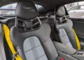 Two black and gray sport seats with yellow seatbelts inside a Porsche 718 Cayman GT4 RS; "Weissach RS" branding is visible on the headrests, highlighting the exclusive Weissach Package.