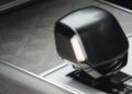 Close-up of a modern car gear shifter on a patterned console, showing part of the drive mode indicator panel—an exclusive touch often found in select Range Rover SV Carmel Edition models or among Exclusive Rovers for sale.