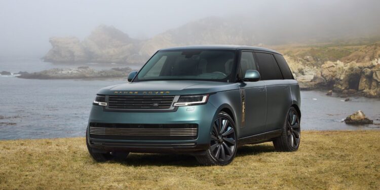 A green Range Rover SV Carmel Edition is parked on grass near a rocky shoreline, with fog and hills in the background—a true highlight among Exclusive Rovers.