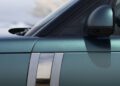 Close-up of the side of a metallic green Range Rover SV Carmel Edition, showing the door, side mirror, and part of the windshield with two vertical chrome strips—an exclusive Rover designed to impress.