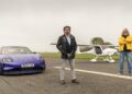 An emotional homecoming: James May and Richard Hammond stand on an airstrip beside a purple car and a small white airplane, having raced to the Top Gear track in EVs on a cloudy day.