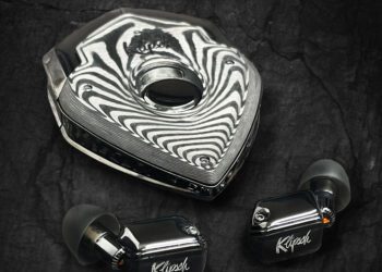 A pair of black Klipsch wireless earbuds with silicone tips are shown next to a metallic, triangular storage case with a reflective pattern—perfect luxury accessories to upgrade your style.