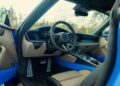 The interior of a modern 992.2 Carrera, featuring the steering wheel, dashboard, pedals, and beige and blue upholstery—an elegant setting that hints at TECHART performance upgrades beneath the surface.