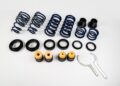A TECHART suspension coilover kit for the 992.2 Carrera is laid out on a white surface, featuring metal springs, rubber bushings, bump stops, black rings, and two silver wrenches—perfect for performance upgrades.