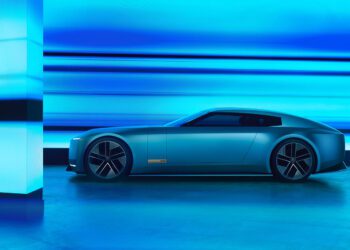 A sleek, modern Jaguar electric car, inspired by the Type 00 Concept, is parked indoors, illuminated by blue lighting and reflective surfaces like a Tokyo Art Installation.