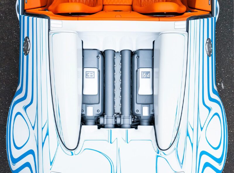Top-down view of a Bugatti Veyron Grand Sport Vitesse engine compartment with white and blue exterior detailing and orange interior seats visible in this unique 1-of-1 masterpiece.
