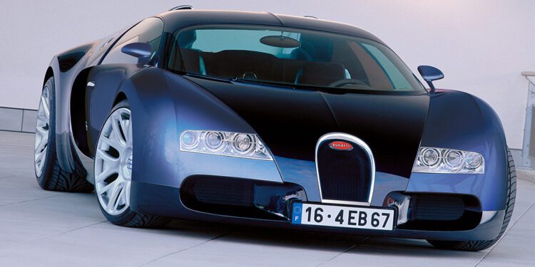 A blue and black Bugatti Veyron hypercar is parked on a tiled surface in front of a plain light-colored wall.