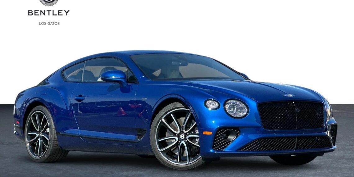 A blue Bentley Continental GT coupe is parked on a paved surface with the Bentley Los Gatos logo in the background.