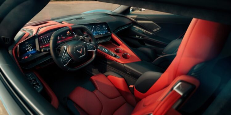 View of a modern 2026 Chevrolet sports car interior featuring red and black leather seats, digital dashboard, and a steering wheel with a Corvette logo.