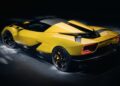 A yellow sports car with black accents is parked on a dark surface, viewed from the rear left side under focused lighting—Italy’s latest V12 supercar packs quad turbos, 2100+ HP, a manual, and rear wheel drive.