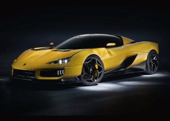 A yellow sports car with black accents, photographed in a dark studio setting with accent lighting highlighting its sleek design—Italy’s Latest V12 Supercar redefines luxury and performance.