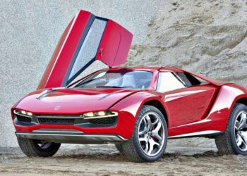 A red sports car with its driver's side scissor door open is parked on sandy ground in front of a rocky backdrop, hinting at Audi Eyes Sale Of Italdesign In Wake Of Cost-Cutting Drive.