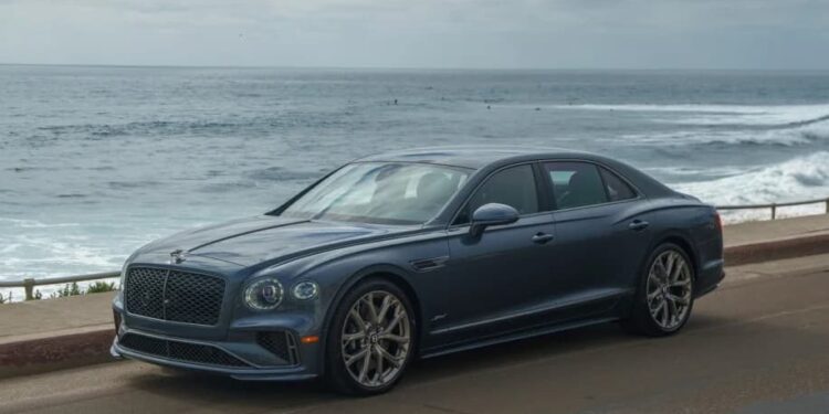 A blue luxury car sedan parked on a coastal road, with the ocean and a cloudy sky in the background—an ideal choice for those browsing exotic car for sale listings.
