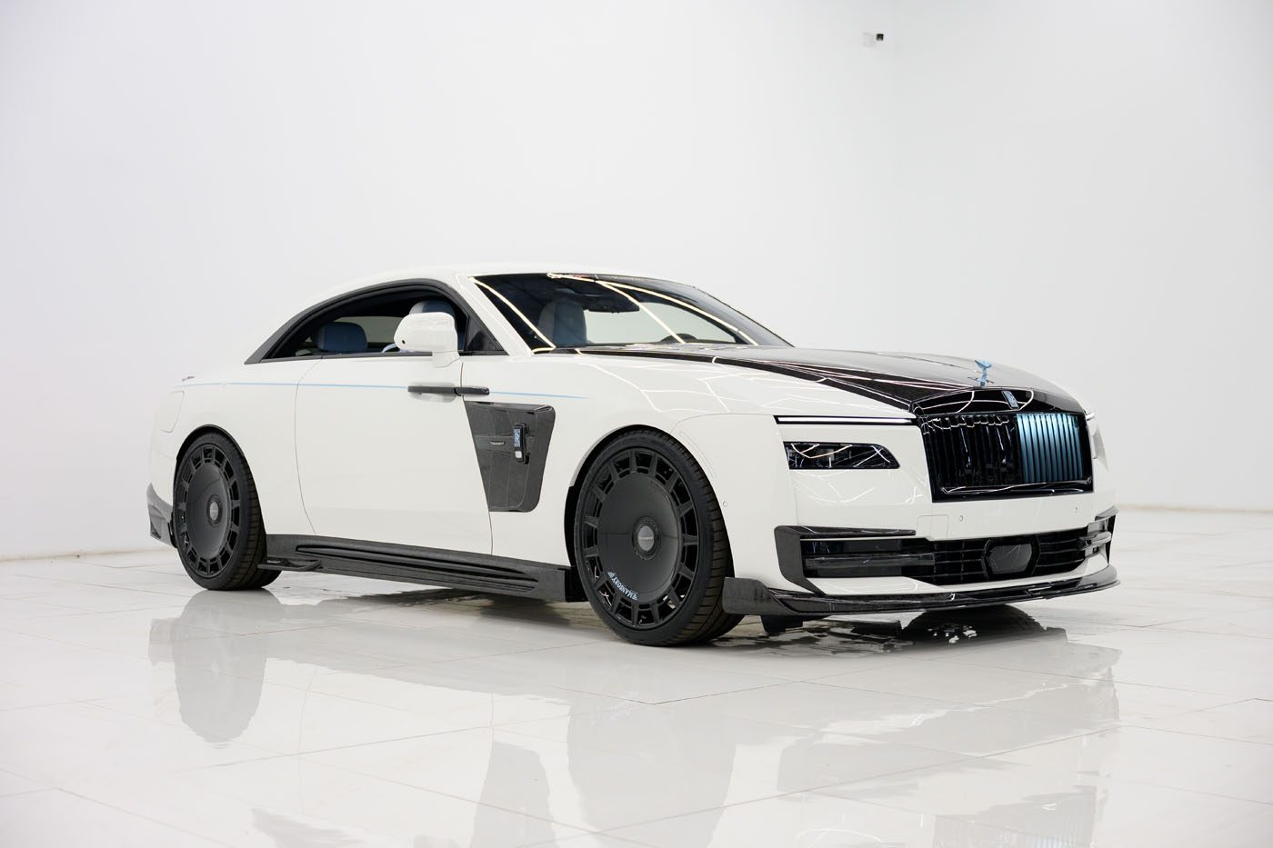 A white and black 2025 Cullinan luxury coupe with a sleek, modern design is parked in a bright, minimalistic indoor space at a Mansory Dealer.