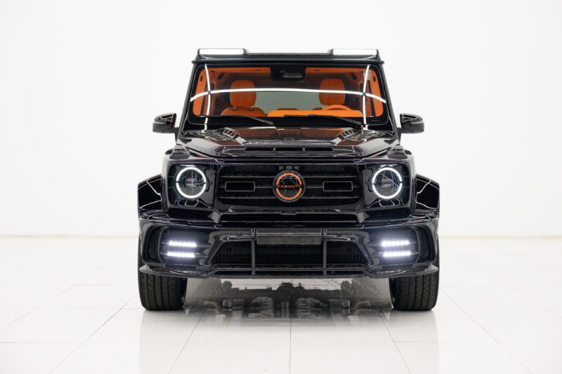 Front view of an exclusive 2025 Cullinan customized black SUV with orange interior accents, LED headlights, and a wide body kit, photographed in a white studio. Available through a certified Mansory dealer.