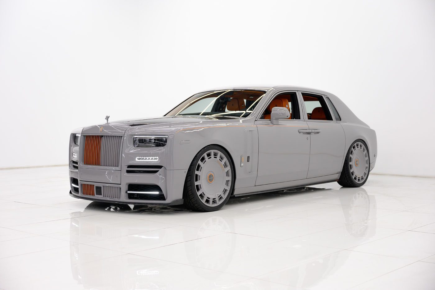 A customized gray 2025 Cullinan sedan with large wheels, tinted windows, and brown accents is parked in a white studio setting for a Limited Spec showcase at a Mansory Dealer.