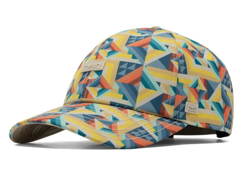 A baseball cap with a colorful geometric pattern in yellow, blue, teal, and red tones; an ideal piece of outdoor gear featuring two small rectangular logo patches on the front and side.