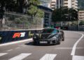 A black Rimac Nevera with Croatian license plates drives on a city racetrack with F1 75 and Monaco Grand Prix banners along the fence.