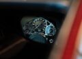 Close-up view of a luxury car dashboard featuring analog dials and a digital odometer reading 000, framed by part of the car’s interior in a Bugatti on display at a Washington D.C. showroom.