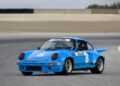 A blue vintage Porsche race car with the number 8 on the hood and doors speeds down Laguna Seca’s racetrack, evoking memories of classic IROC All-Star battles.