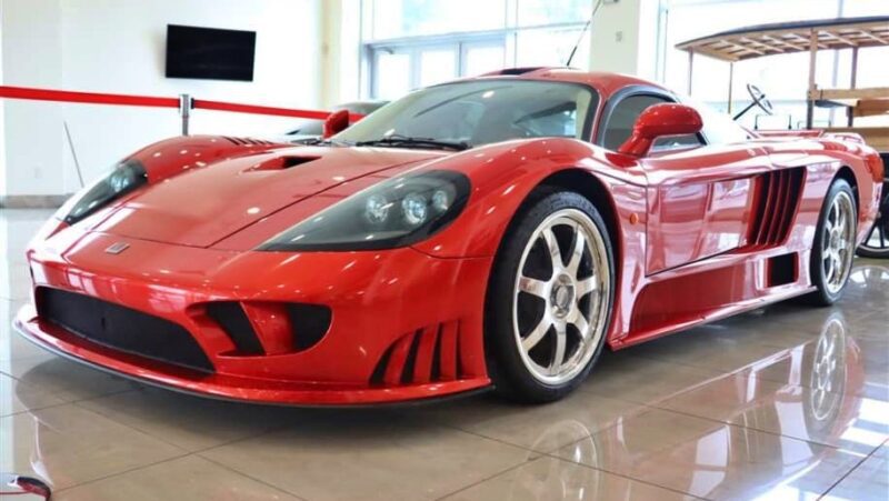 A red Saleen S7 supercar, one of the best manual supercars, is displayed indoors on a shiny tile floor, featuring sleek aerodynamic lines and silver alloy wheels.