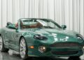 A green convertible sports car with the top down is parked indoors in front of white curtains, showcasing one of the classic automotive color combos often sought after by enthusiasts searching for standout cars for sale.