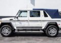 A Mercedes-Maybach G650 for sale, this white luxury SUV with a blue soft-top roof is parked in front of a gray and white wall.