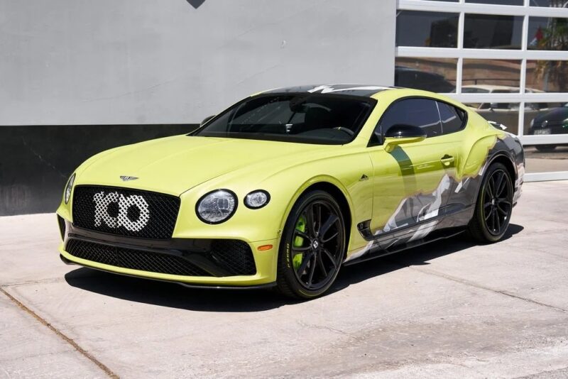 A lime green Bentley Continental GT, one of the best Bentleys, is parked on a concrete surface in front of a modern building with glass-panel garage doors.
