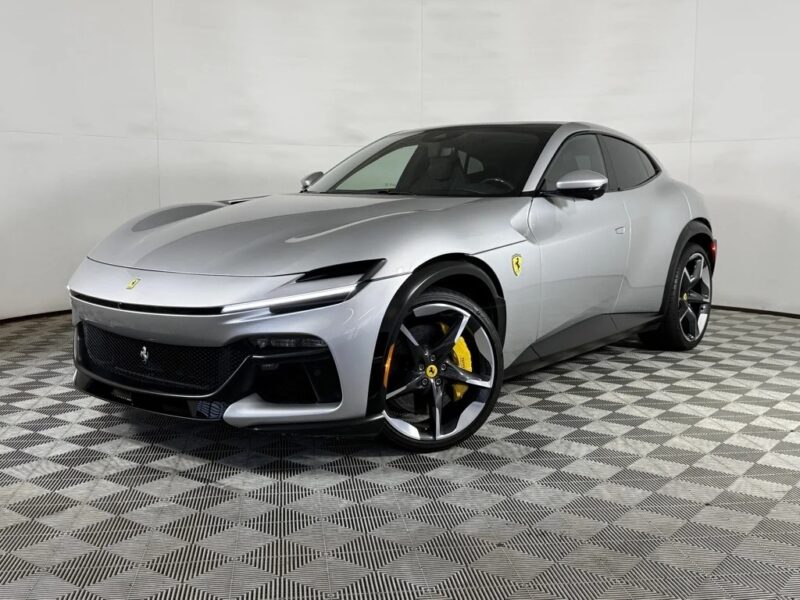 A silver Ferrari Purosangue SUV is parked in a showroom with a checkered floor, featuring yellow brake calipers and Ferrari emblems—a standout among the best Ferrari SUVs for sale.