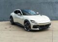 A white Ferrari Purosangue SUV is parked on a concrete surface in front of a gray wall, showcasing why it’s among the best Ferrari SUVs for sale.