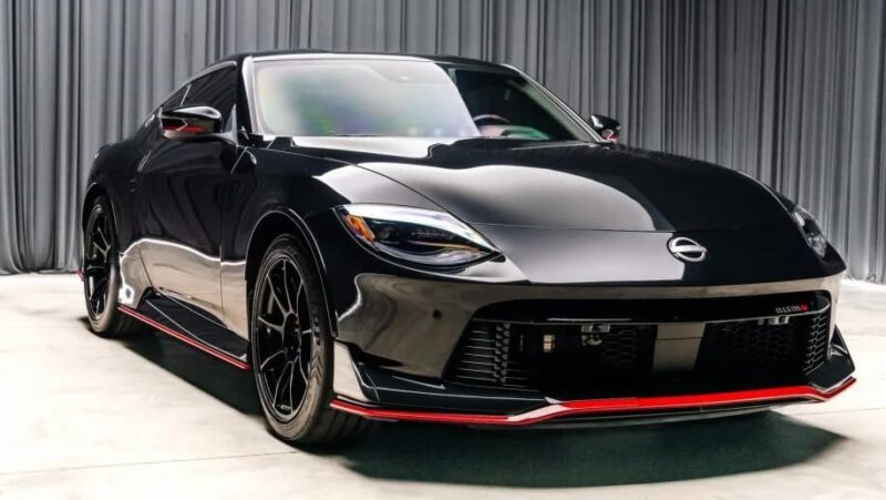 For Sale: Best Sports Car Under $100k—a black Nissan with striking red accents, parked indoors on a concrete floor with a gray curtain backdrop.