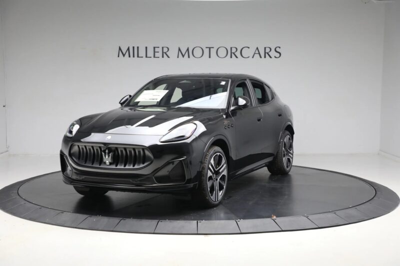 A black Maserati Grecale SUV, an icon of Italian luxury, is displayed on a rotating platform in a showroom with "Miller Motorcars" on the wall in the background.
