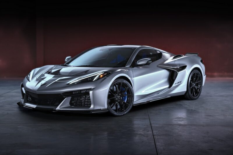 A silver sports car with black accents is parked in an indoor setting with a dark red and black background, hinting at the power behind it—revealed: 2026 Corvette ZR1X, the most powerful Chevrolet ever built.