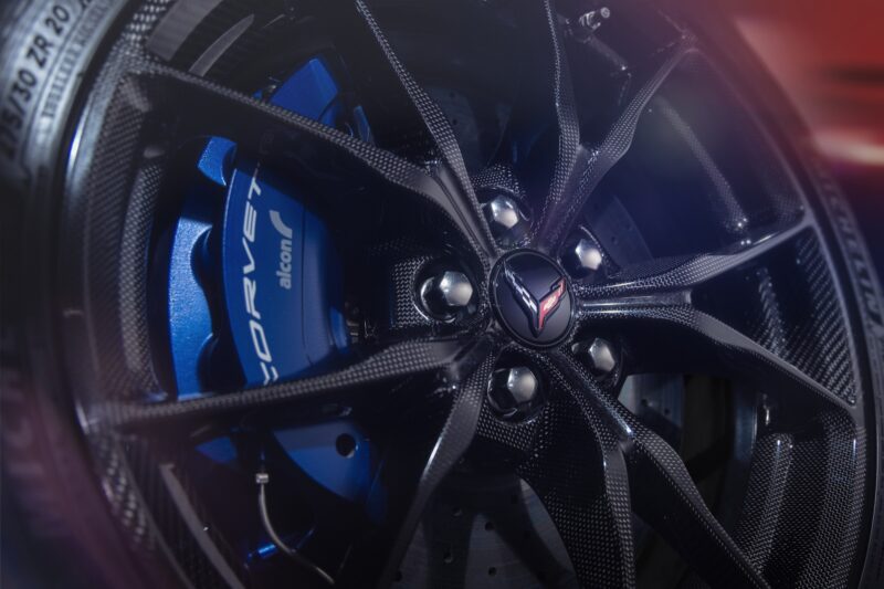 Close-up of a Corvette wheel with a carbon fiber rim, blue Alcon brake caliper, and the Corvette emblem—hinting at the power behind the revealed: 2026 Corvette ZR1X, the most powerful Chevrolet ever built.