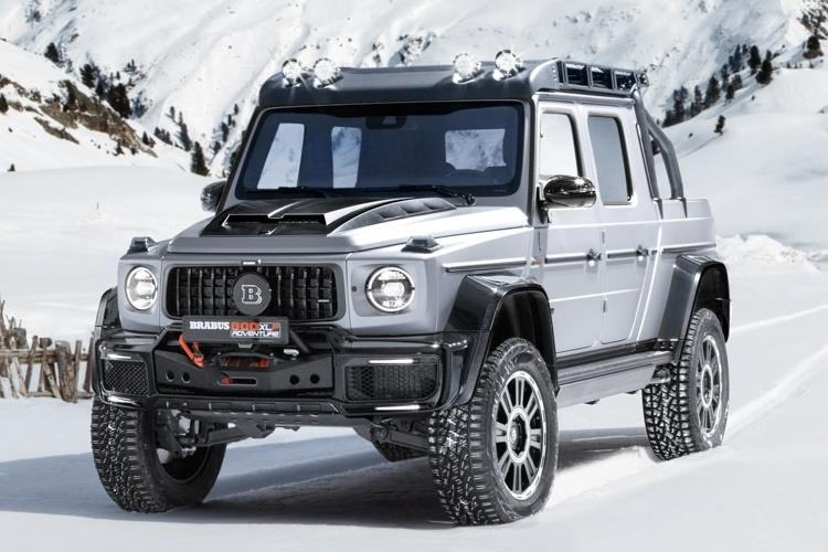 The Mercedes-Benz Silver Silver truck highlights a unique creation on snow terrain with mountains in the background, between cars designated for sale.