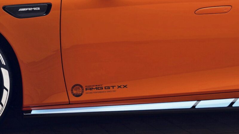 Close-up of the lower side panel of an orange Mercedes EV AMG GT XX, showing the AMG badge, concept label, and distinctive side skirt detailing—highlighting its impressive 341 HP performance.