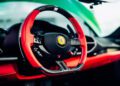 Close-up of a Ferrari 296 GTS steering wheel featuring red and black accents, carbon fiber details, and visible control buttons—a modern tribute to sports car design.